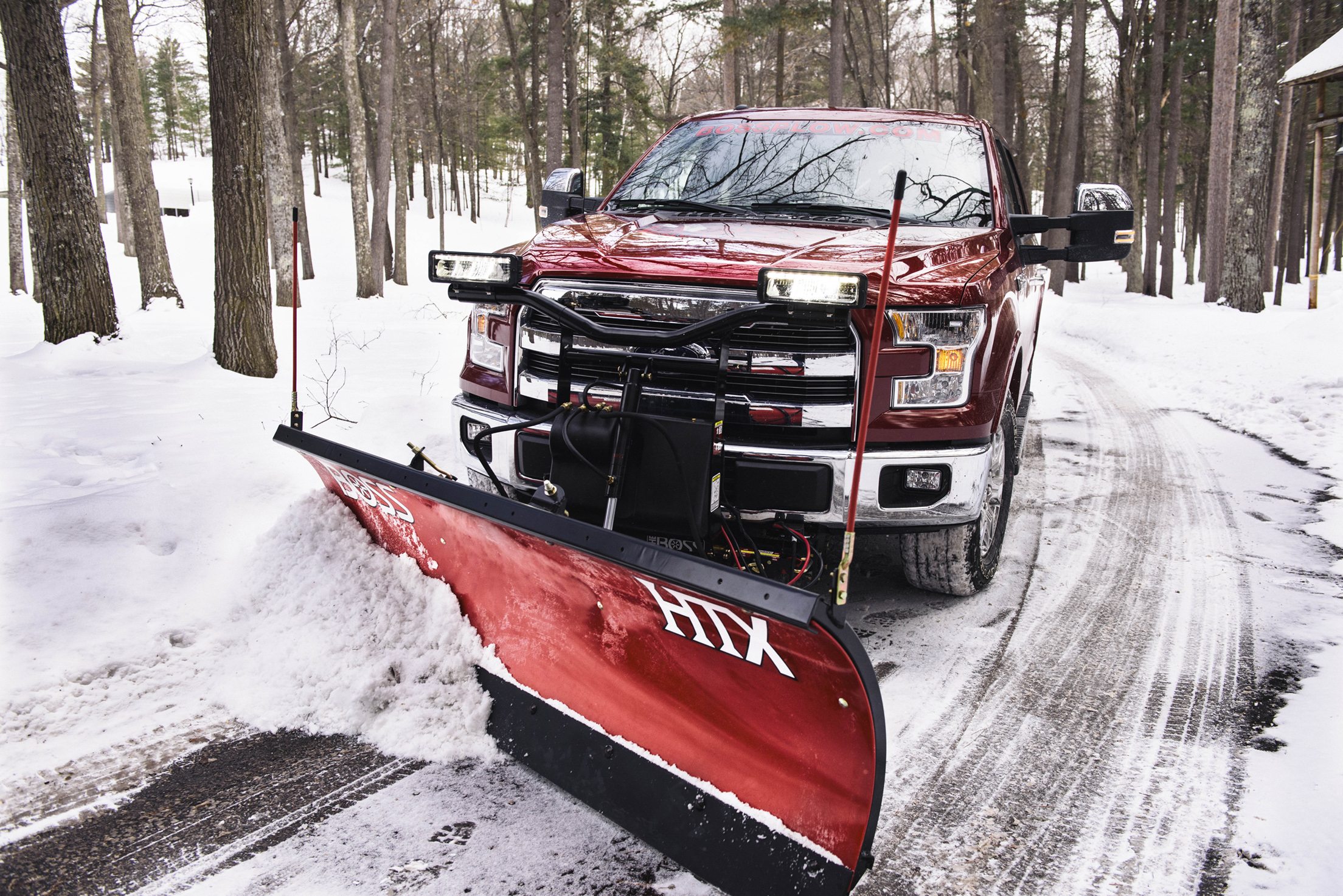 red truck with red snow plow clearing road
